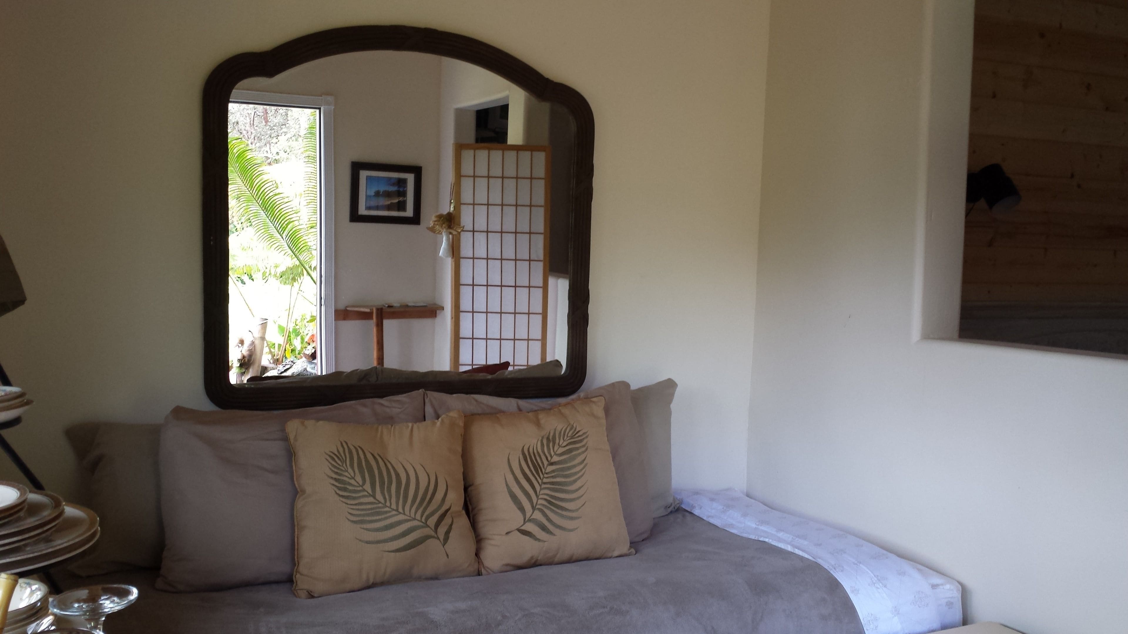 A room with a sofa, a mirror, a small table, and a view of a traditional Japanese room.