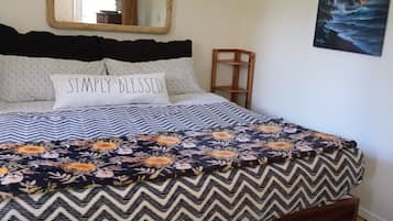 A bedroom with a bed, a mirror, a chair, and a painting on the wall.