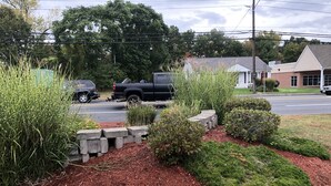 A landscaped garden area with mulch, shrubs, and a concrete pathway. - Wilbraham Inn (Wilbraham)