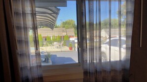 A window with a view of a parking lot and a building with outdoor furniture. - Wilbraham Inn (Wilbraham)
