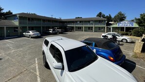 A motel with a two-story structure, a parking lot, and several parked vehicles. - Villa West Motel (Florence)