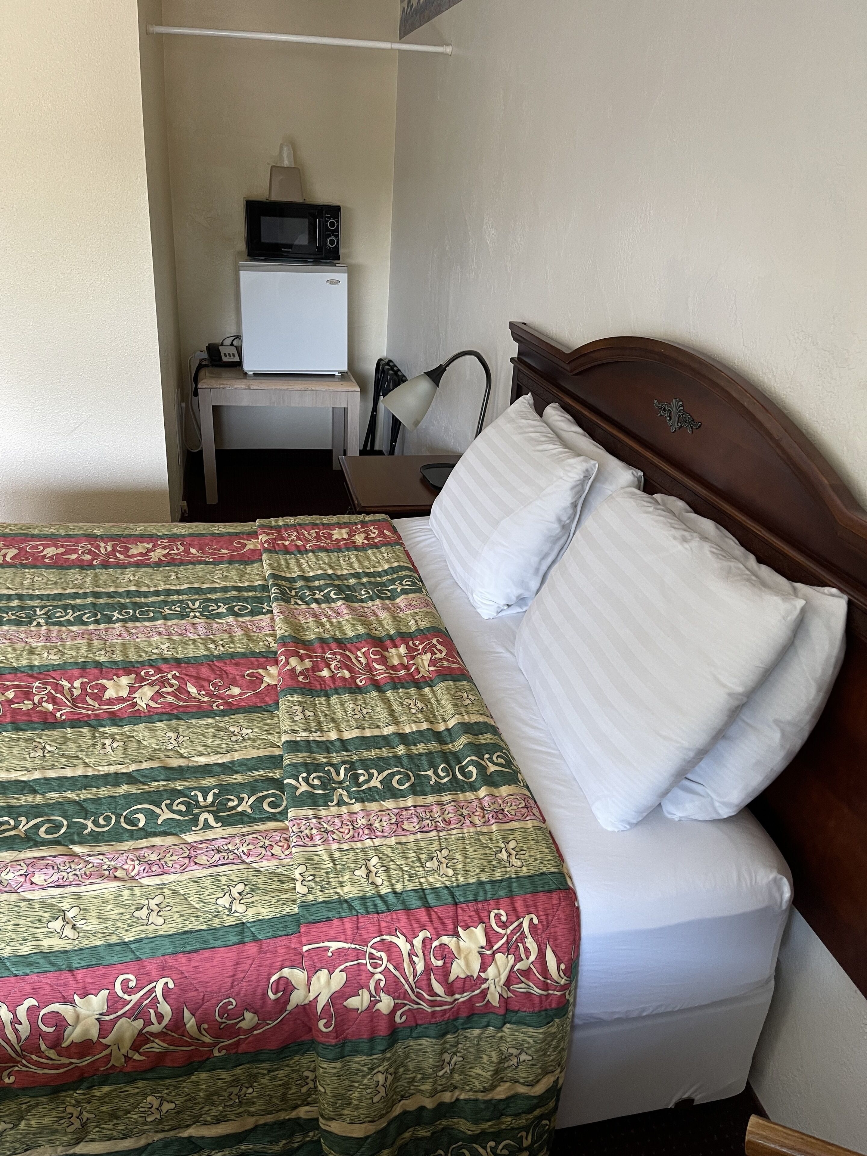 Une chambre d’hôtel avec un lit, un bureau doté d’un micro-ondes et une chaise.