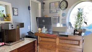 A hotel room with a wooden desk, a computer, a clock, and a window with a view. - Villa West Motel (Florence)