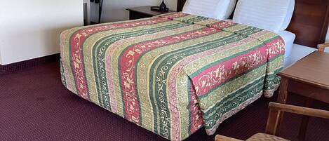 Una habitación de hotel con una cama, un escritorio, una silla y una mesita de noche.
