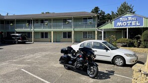 A motel with a two-story structure, a parking lot, and a motorcycle parked in front. - Villa West Motel (Florence)