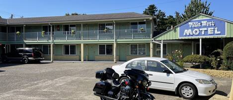 Un motel con una estructura de dos pisos, un estacionamiento y una motocicleta estacionada al frente.