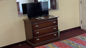 A hotel room with a bed, a dresser, a television, and a mirror.