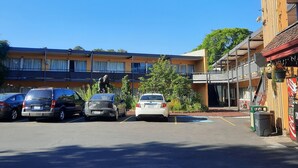 A parking lot with several cars, a building with multiple floors, and a Coca-Cola vending machine. - Longview Inn (Longview)