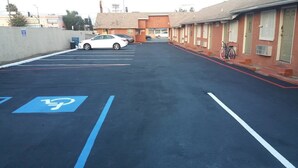 A parking lot with marked handicapped spaces and a building with a brick facade in the background. - Crenshaw Inn Motel (Los Angeles)