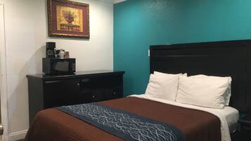 Une chambre d’hôtel avec un lit, une commode, un four à micro-ondes et un tableau encadré au mur.