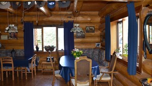 Una baita in legno con zona pranzo, che include un tavolo rotondo, sedie e una tovaglia blu.