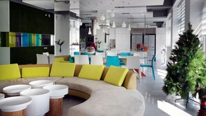 A modern living room with a curved sofa, multiple white coffee tables, and a Christmas tree. - La Palette (Luodong)