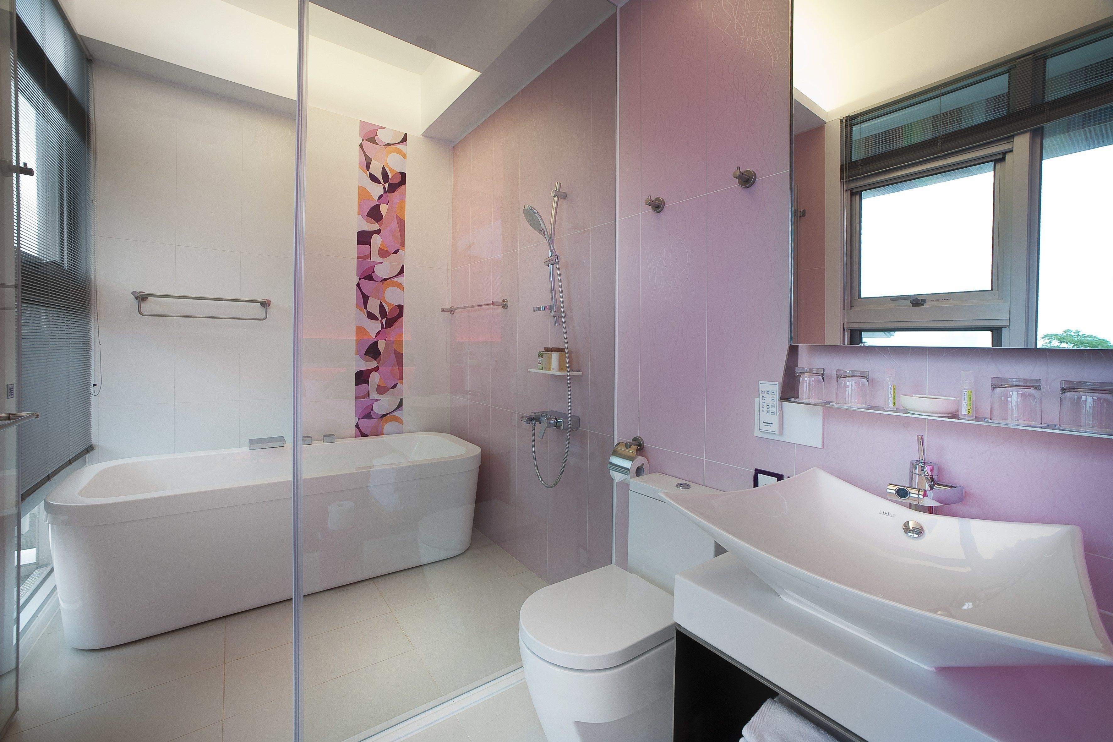 A modern bathroom with a freestanding bathtub, a separate toilet, and a vanity with a mirror.