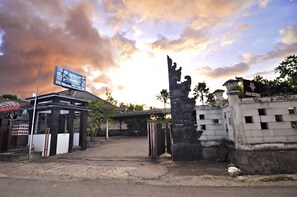 A hotel entrance with a traditional gate, a signboard, and a clear sky.