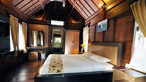A hotel room with a large bed, a desk, a mirror, and a television. - Aman Gati Hotel Balangan (Jimbaran)