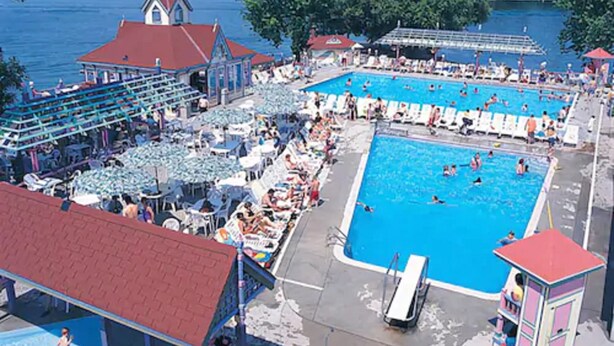 A large outdoor swimming pool with multiple lanes, surrounded by lounge chairs and umbrellas. - Fern Resort (Ramara)