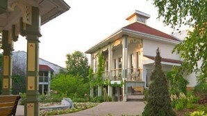 A building with a covered entrance, a garden with flowers, and a bench. - Fern Resort (Ramara)