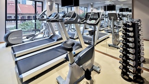 Une salle de sport équipée de tapis de course, de vélos d’exercice et d’une série de haltères.