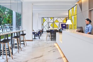 Un moderno vestíbulo de hotel con recepción, zona de estar y amplios ventanales.