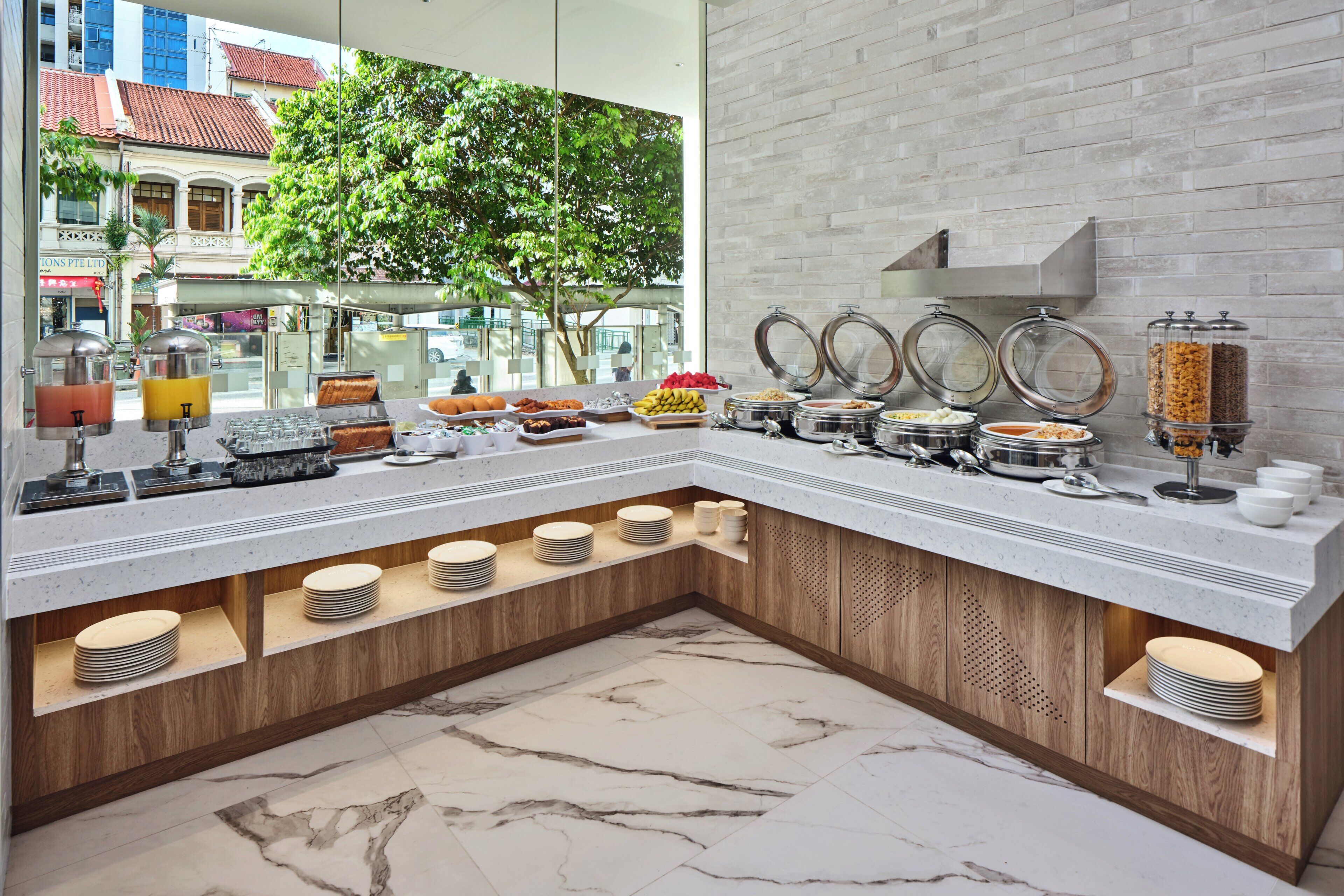 A breakfast buffet with various food items and a marble-tiled floor.