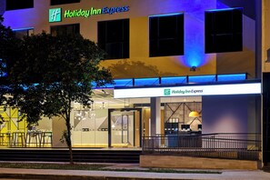 Een Holiday Inn Express gebouw met een moderne gevel, grote ramen en een goed verlichte entree.
