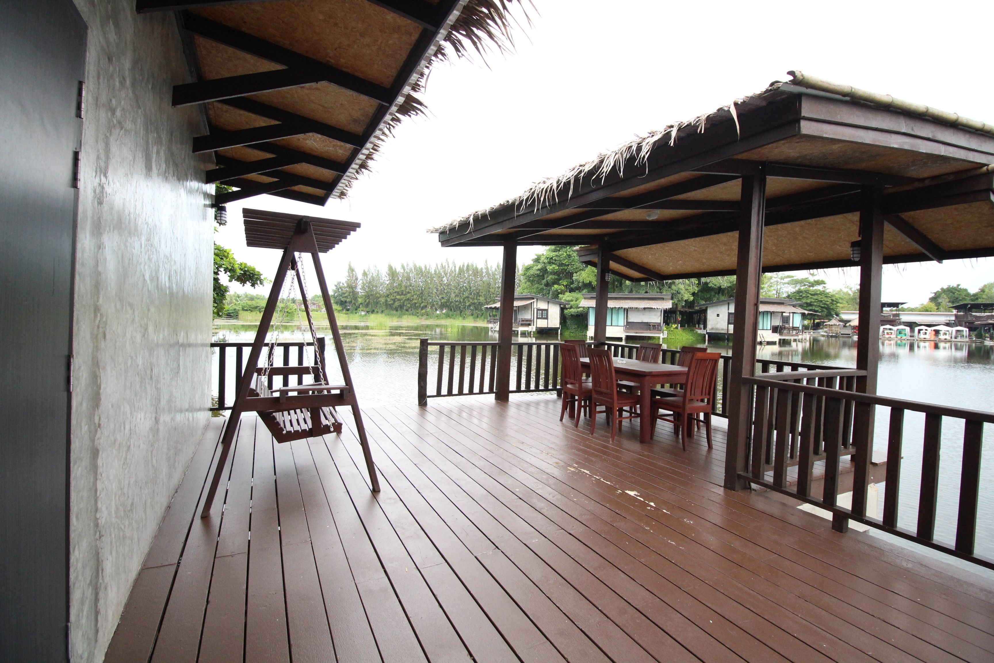Una terraza de madera con una mesa y sillas, con vista a un cuerpo de agua y edificios al fondo.