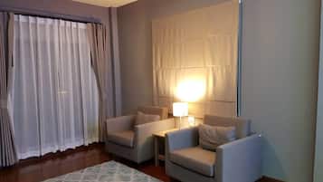 Habitación de hotel con dos sillones, una mesita, una lámpara y un tapete estampado.