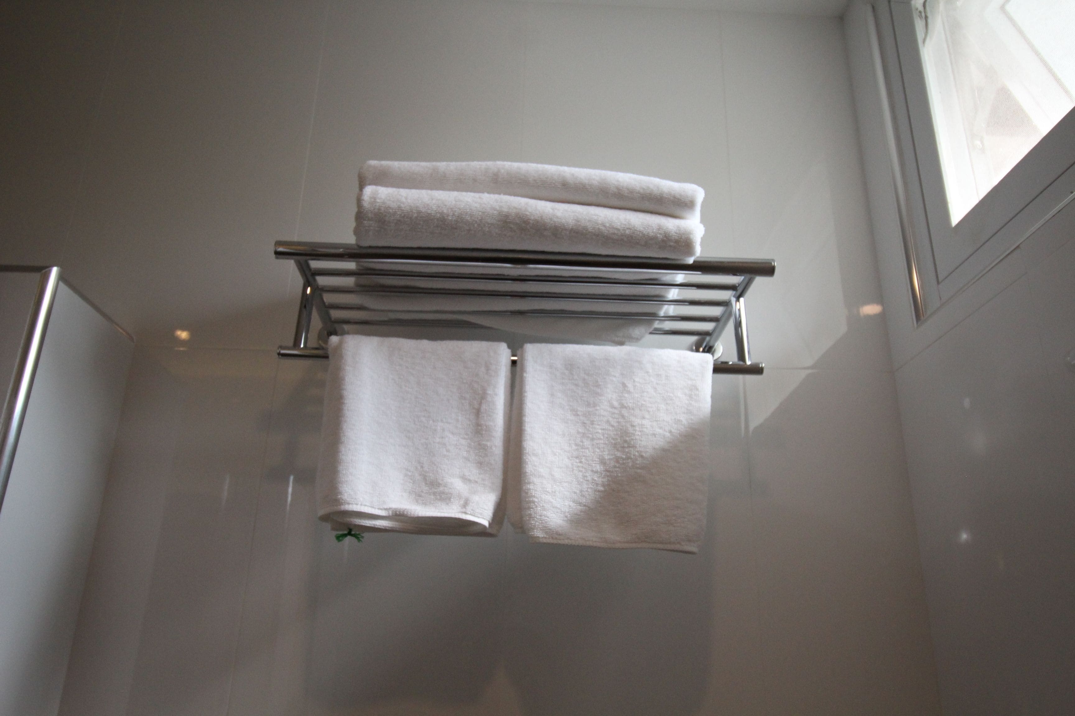 A bathroom with a towel rack holding three folded towels.