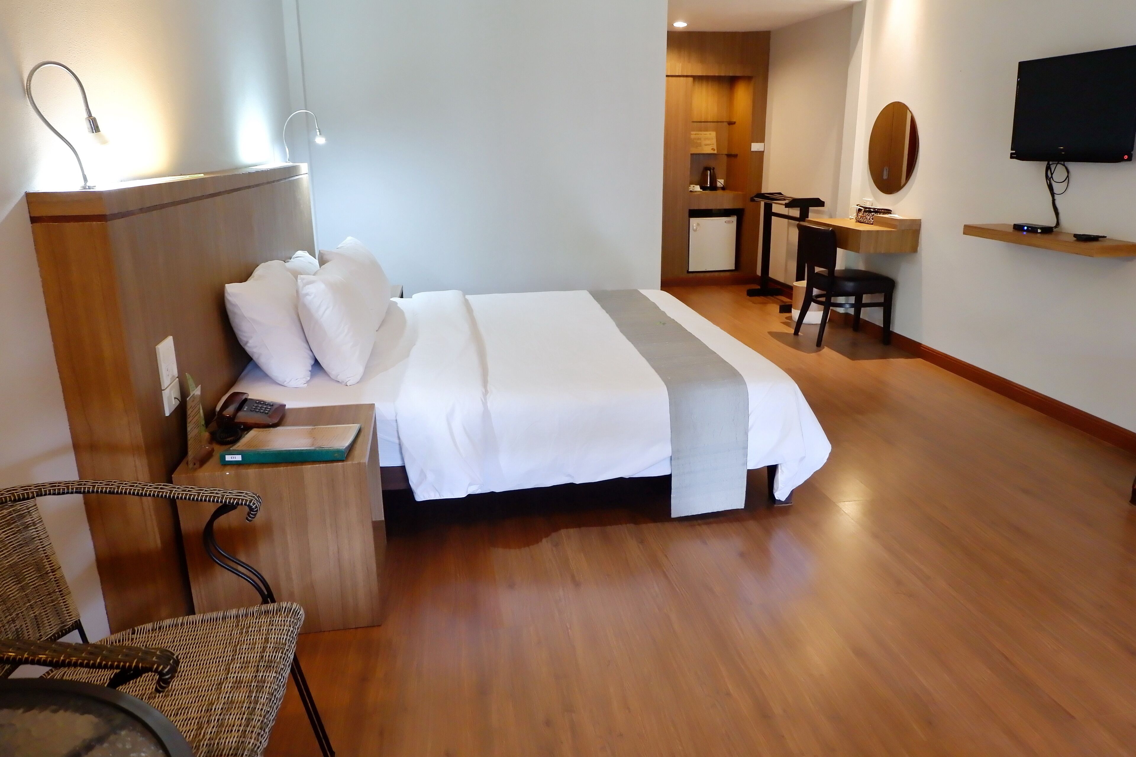 A hotel room with a bed, bedside table, chair, desk, and TV.