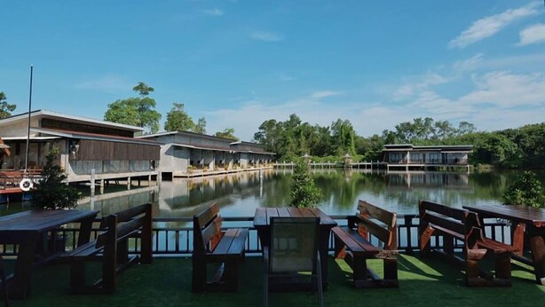 A lakeside hotel with wooden deck seating and a view of the water. - Banpu Resort Trat (Trat)