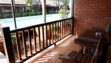 A wooden deck with a pool view, brick walls, and a wooden bench.