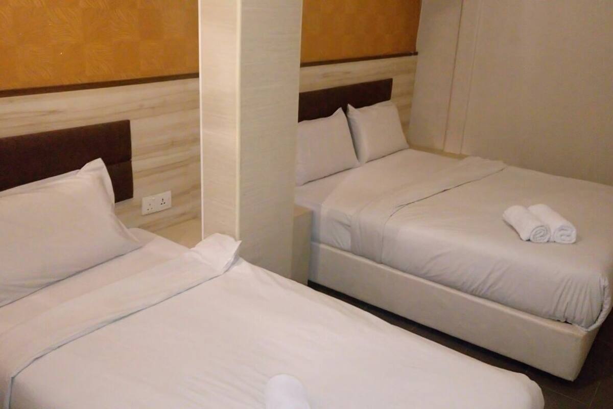 Two single beds with white linens, a wooden headboard, and a small bedside table with a power outlet.