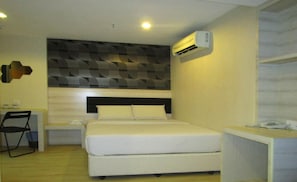A bedroom with a bed, bedside tables, a chair, and an air conditioning unit.