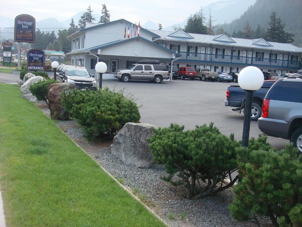 A Heritage Inn with a parking lot, a building with a blue roof, and a mountainous backdrop.