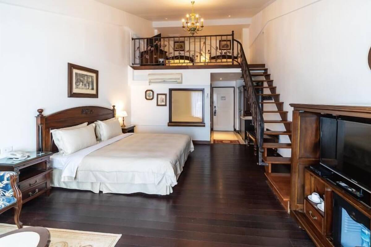 Ein Schlafzimmer mit einem großen Bett, einem Fernseher, einer Holztreppe und einer Chandelüstere.