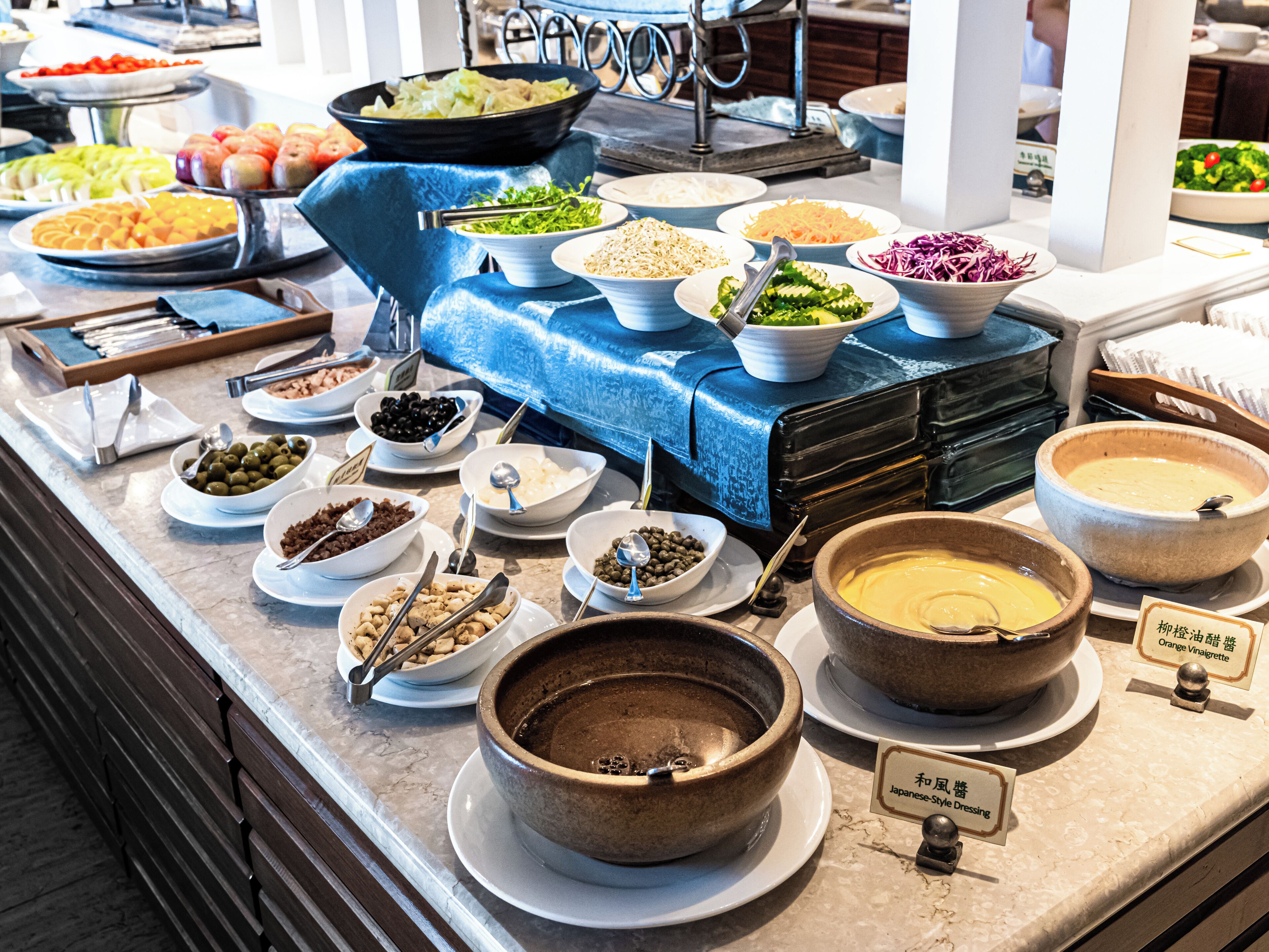A buffet with various dishes and a blue cloth-covered table.