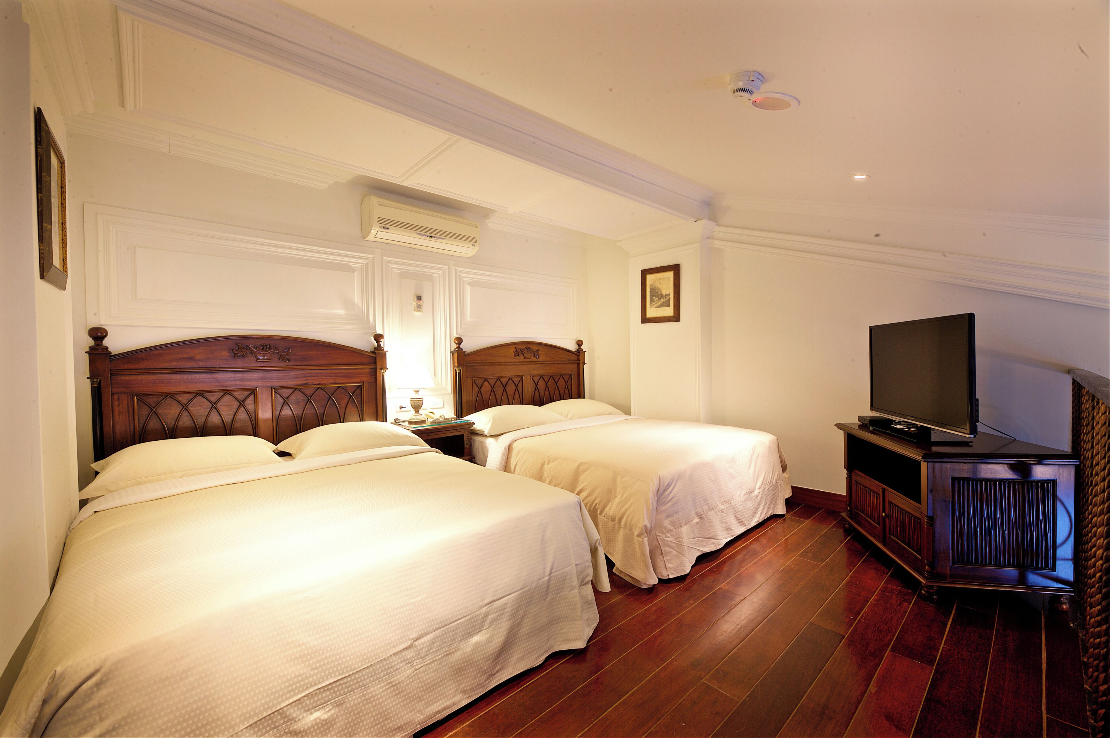 Habitación de hotel con dos camas, un televisor y un armario de madera.