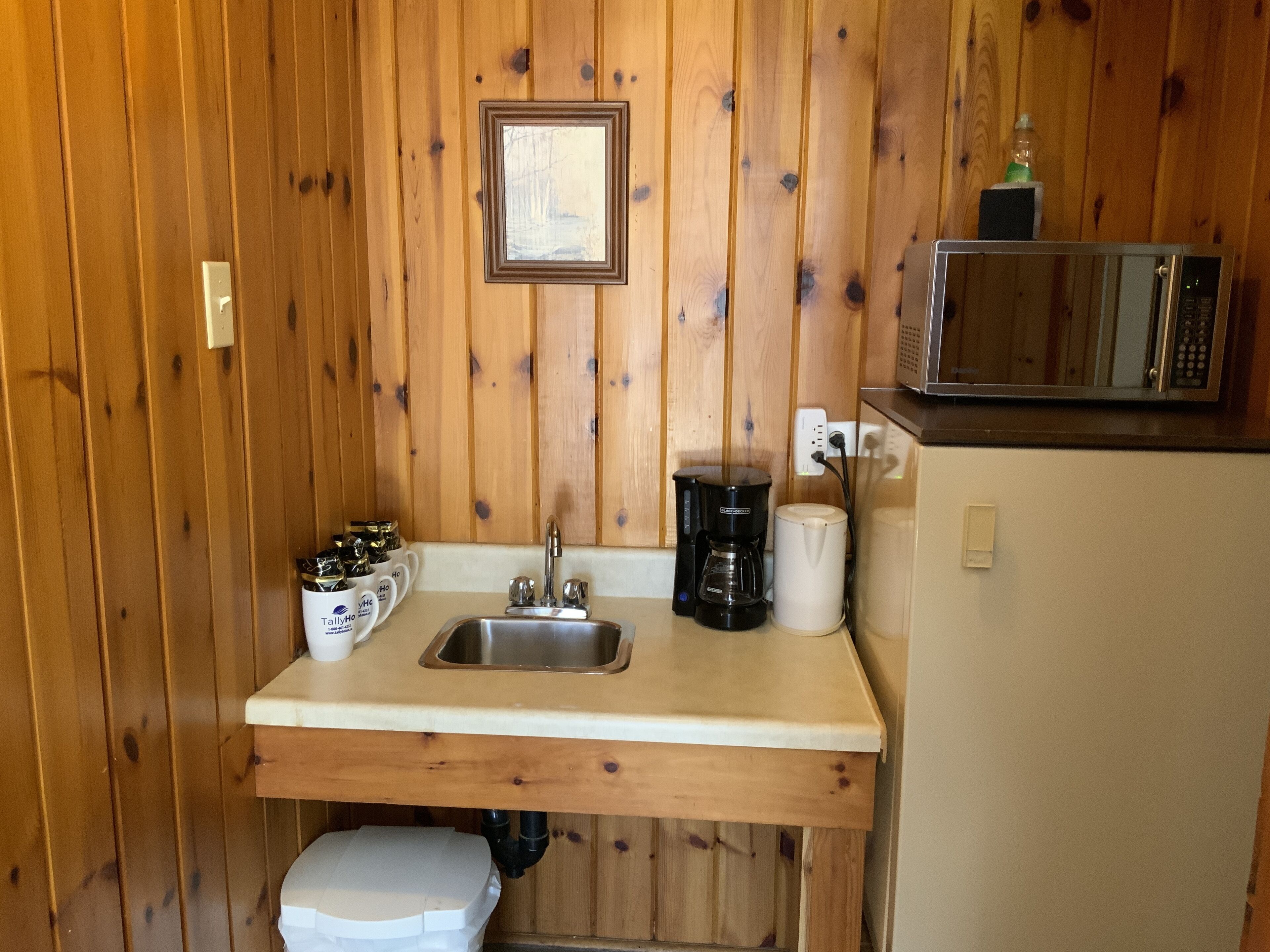 A compact kitchenette with a sink, coffee maker, and microwave.