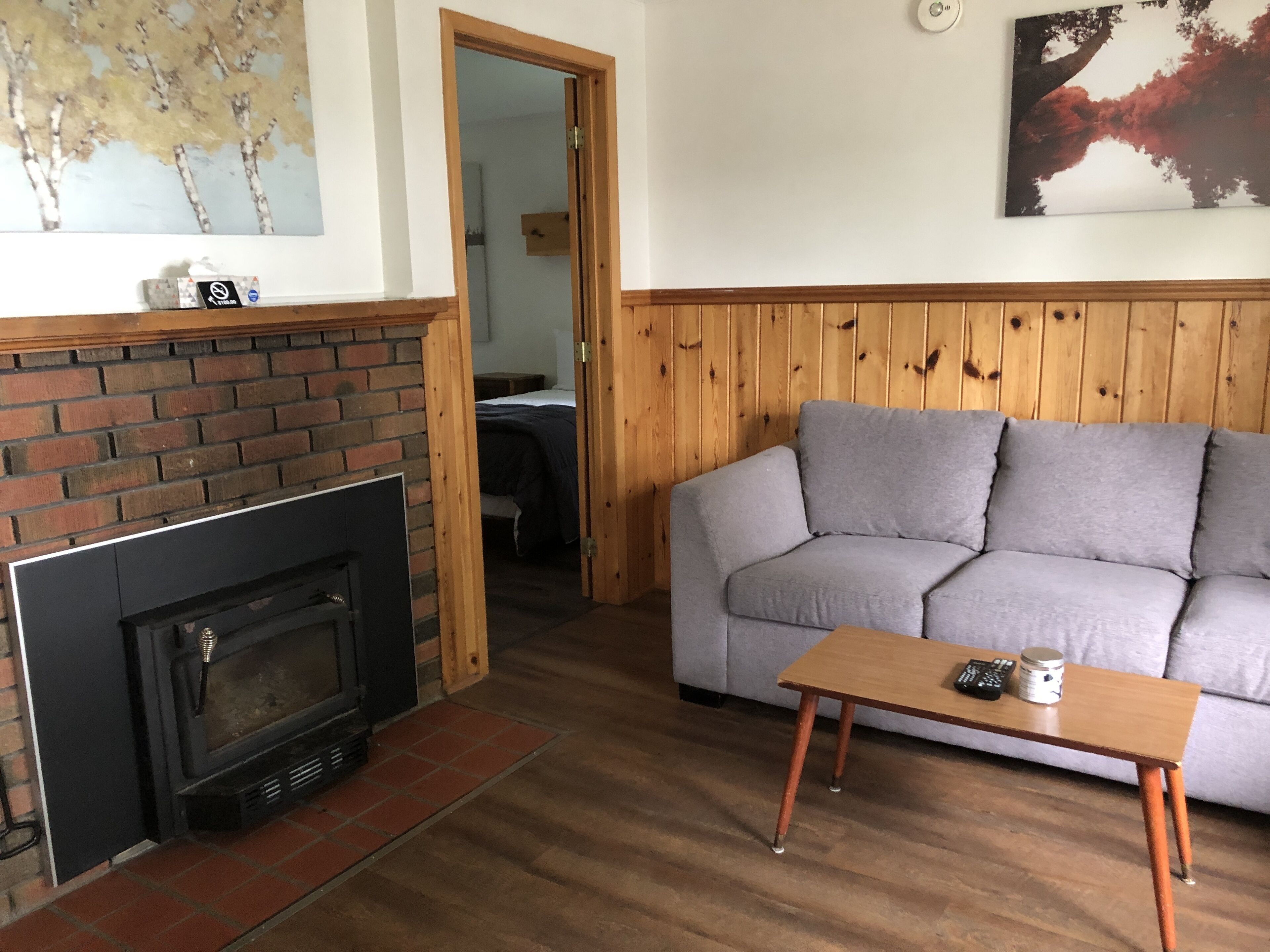 En stue med en murstenspejs, en grå sofa og et træbord.