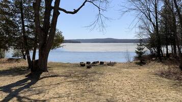 A lakeside campsite with trees, a clear sky, and a distant shoreline.