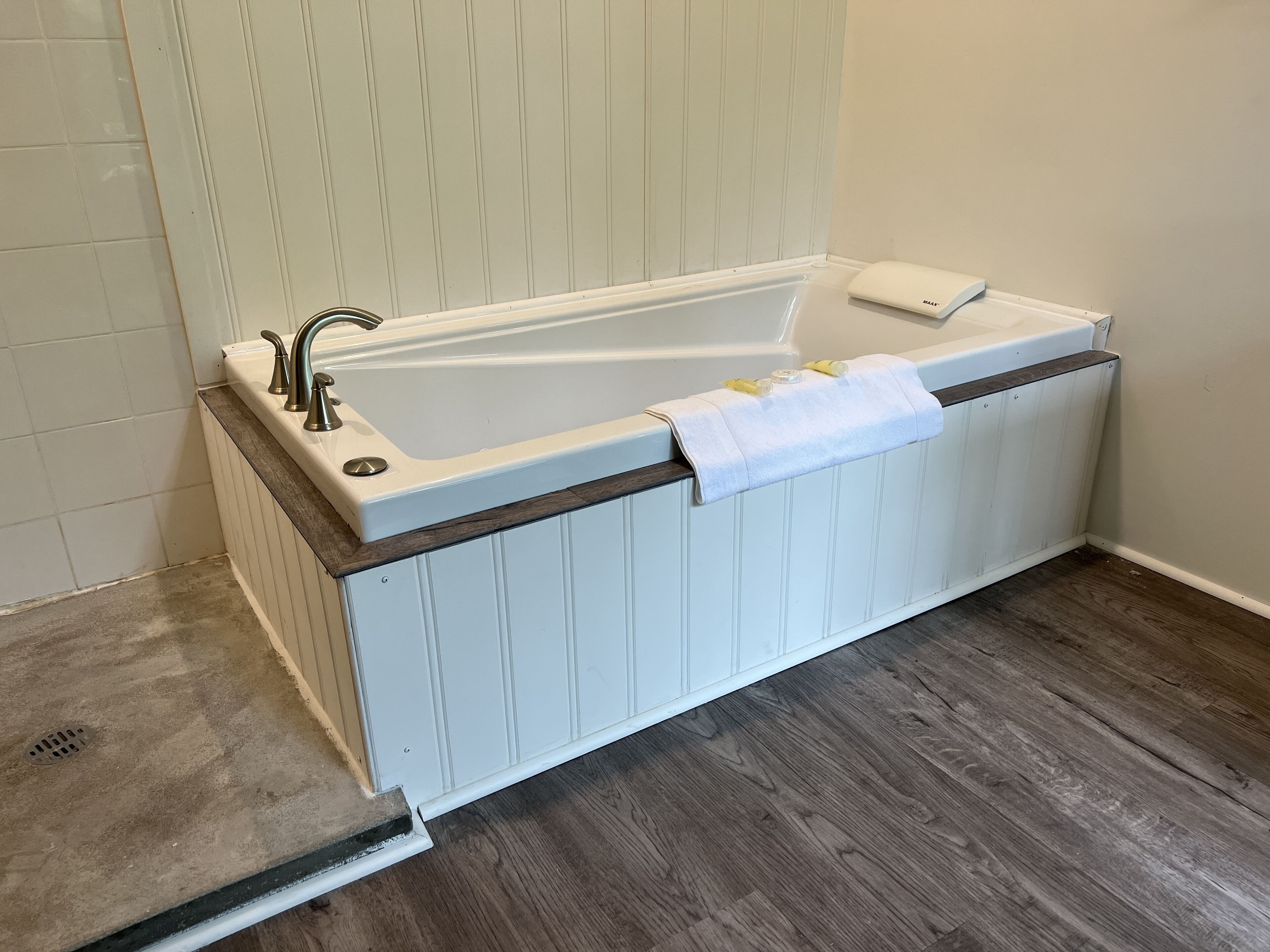 A bathroom with a bathtub, a towel, and a wooden floor.