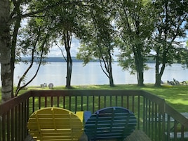Une terrasse avec des chaises donnant sur un lac, entourée d’arbres.
