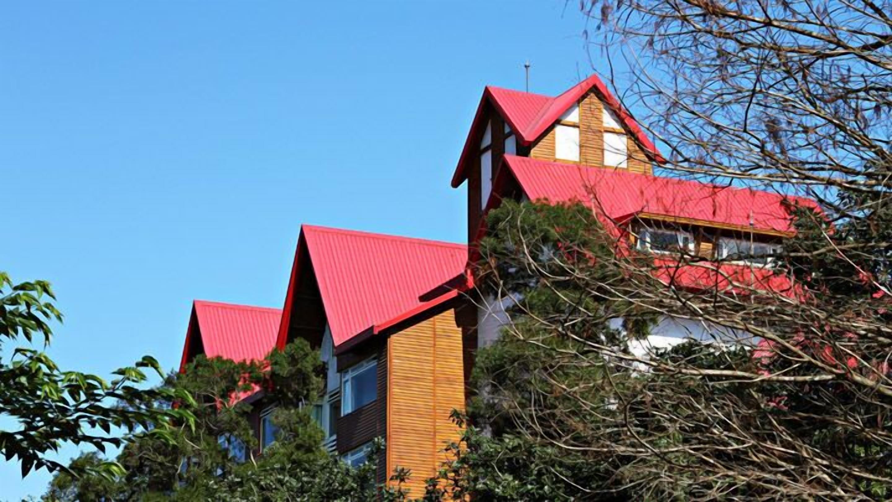 A building with a red roof and wooden facade, surrounded by trees.