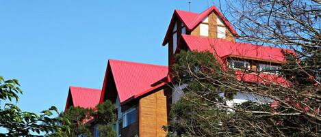 A building with a red roof and wooden facade, surrounded by trees.