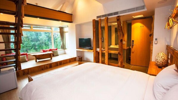 Une chambre à coucher avec un grand lit, un banc en bois, une télévision et une armoire avec un miroir.