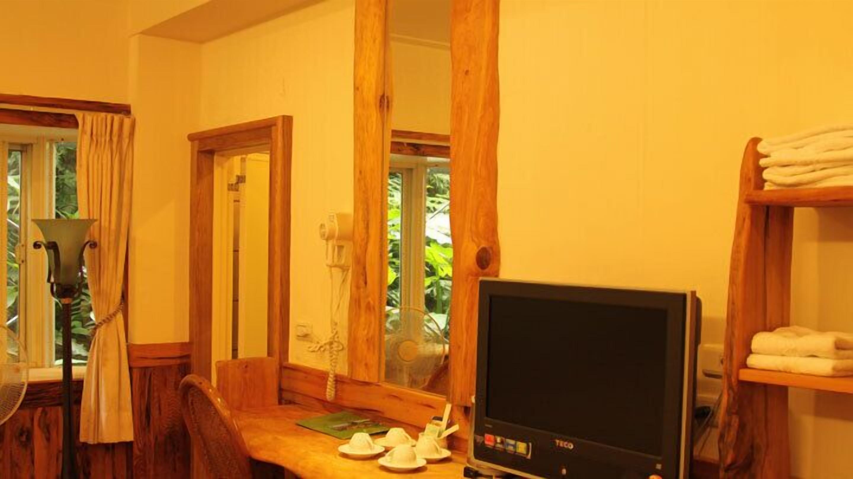 A room with a wooden desk, a television, and a mirror.