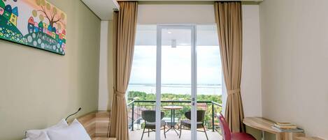 A hotel room with a bed, a desk, a chair, and a balcony with a view.