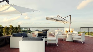 A rooftop terrace with outdoor furniture, including sofas and chairs, and a table with a decorative item. - Mahogany Hotel (Nusa Dua)
