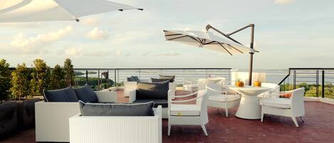 Una terraza en la azotea con mobiliario exterior, incluyendo sofás y sillones, y una mesa con un objeto decorativo.