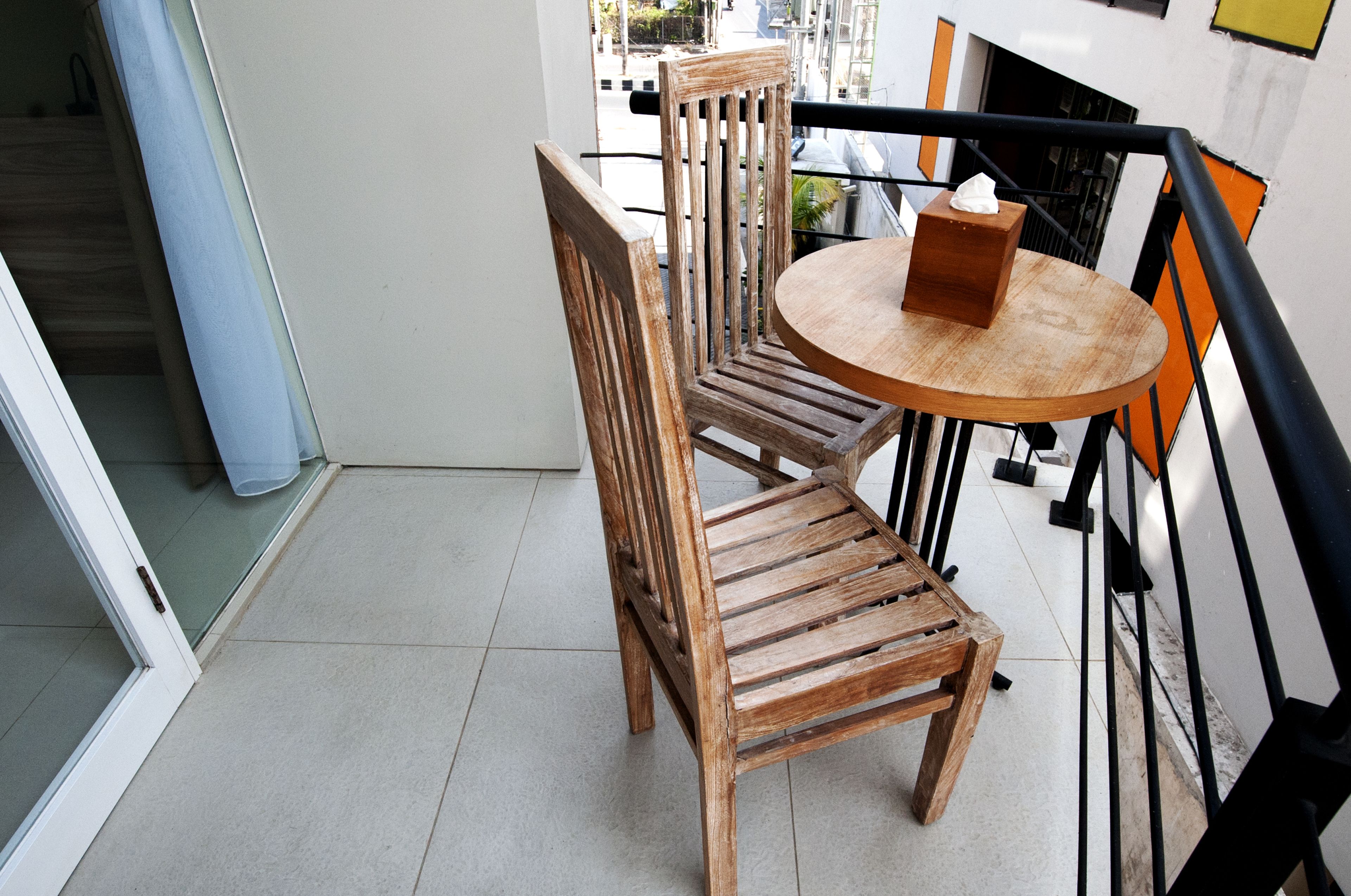 A wooden chair and table on a balcony with a view of the street.
